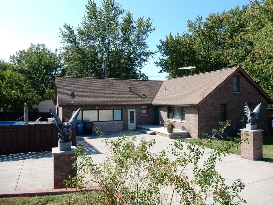 Front view of house, spacious cement driveway, and pool gate from Perryview Dr.