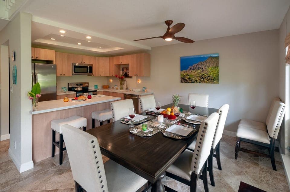 Princeville condos Puamana 25B dining area - In the dining/kitchen area, you can enjoy a sit-down dinner at the 8-seater table, or a casual breakfast at the island. The kitchen is fully-stocked, too, so whipping up a meal is no problem!