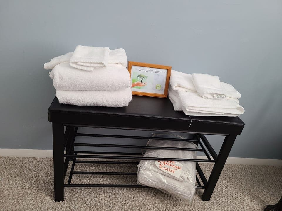 White bath, hand towel & facecloth.  Bench stores lightweight blanket.