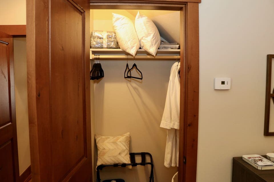Lower level Master suite closet with robes, extra blanket, luggage rack.