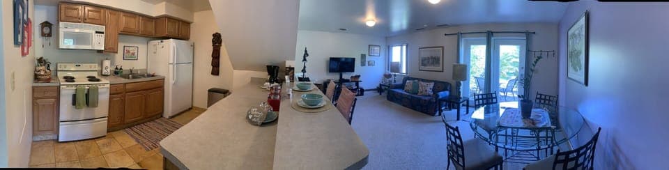 Pano of the fully stocked kitchen, living and dining room overlooking the patio.