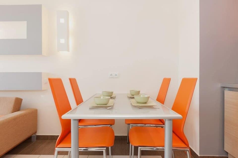 Another view of the dining area with orange chairs, blending seamlessly with the kitchen area for an open, cohesive look.