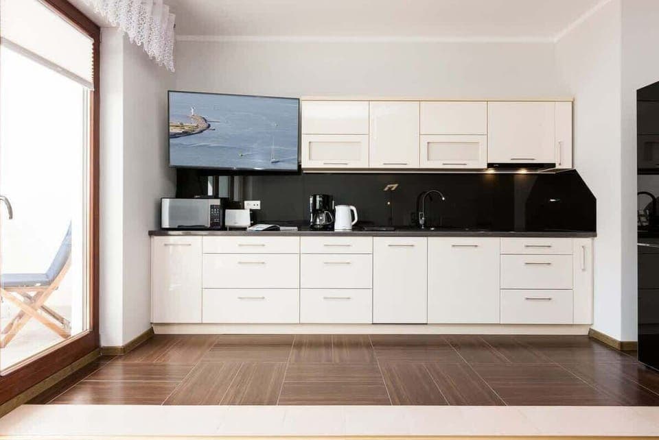 The bright space and functionality of the kitchenette, with its white furniture, allows you to enjoy meals in front of the flat-screen TV.