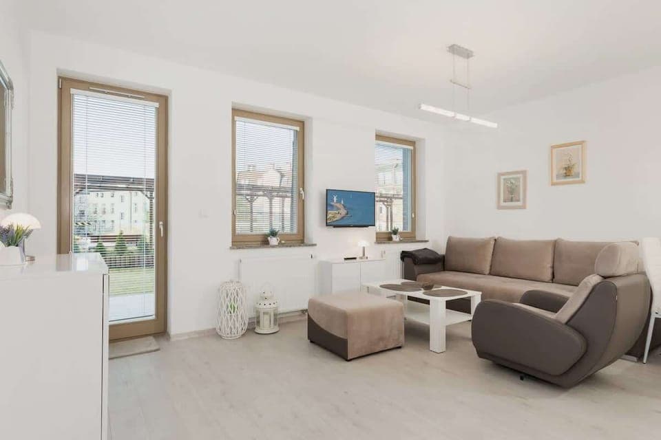 Bright living room with elegant brown double sofa bed, stylish armchair and white coffee table.