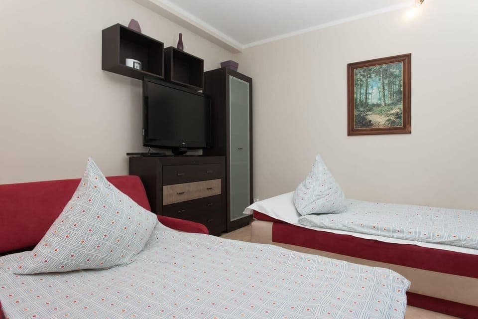 A view of the twin beds from the foot of the room, showing the simple yet cozy bedroom setup. The dark wood furniture and white bedding create a contrast that gives the room a clean, modern look.
