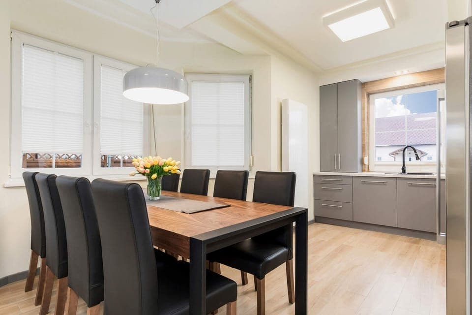 A dining area connected to a living room, featuring a wooden table with four chairs and an open, spacious design.