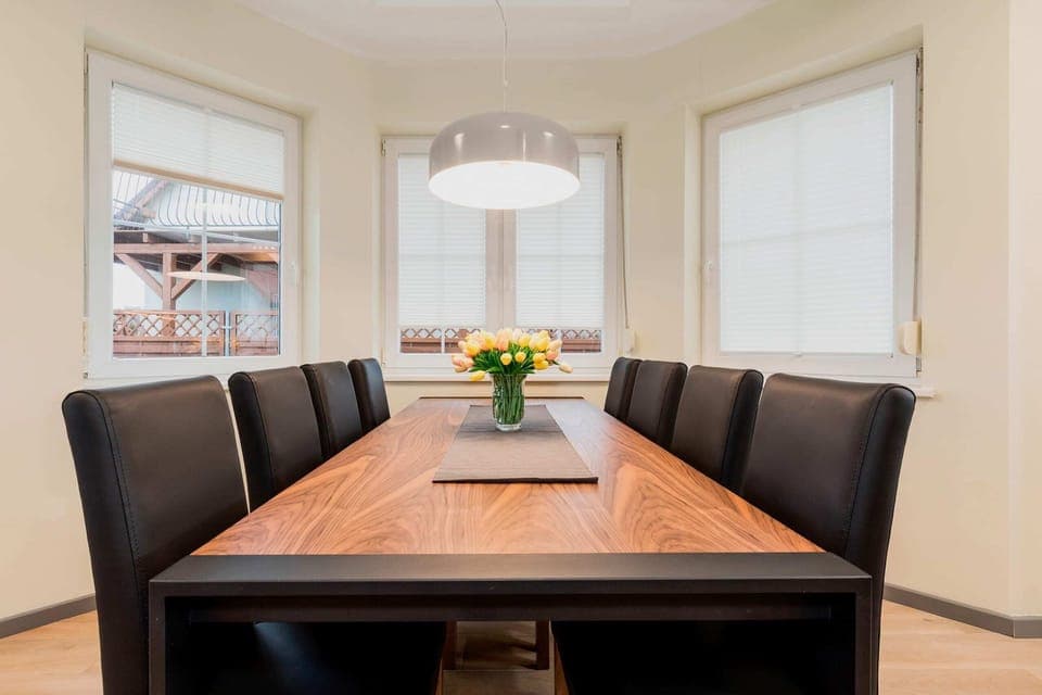 A dining area connected to a living room, featuring a wooden table with four chairs and an open, spacious design.