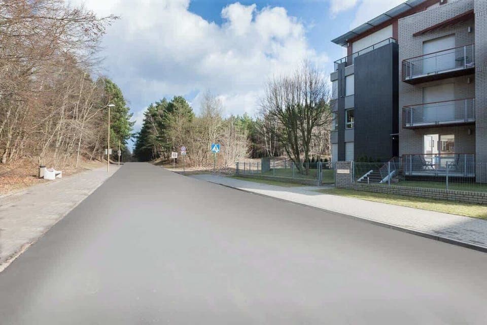 A scenic street view with modern apartment buildings and surrounding greenery, creating a serene environment.