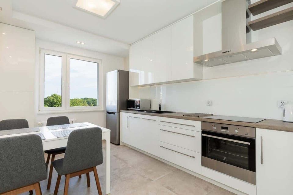 A kitchen area with white cabinets and a small breakfast nook, offering both cooking and dining spaces in one.