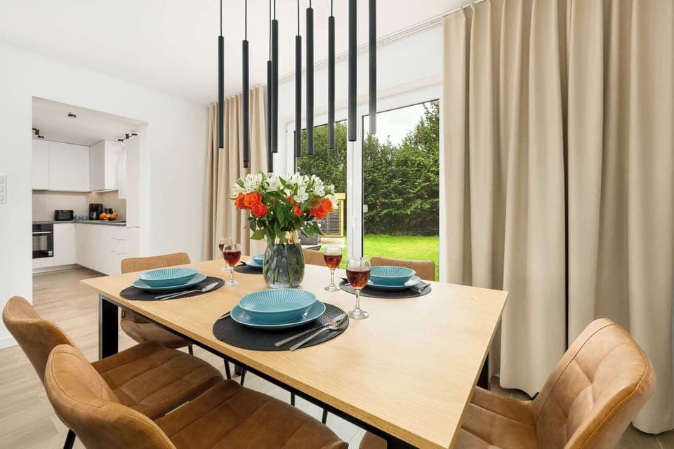 The wooden table set with tableware and fresh flowers invites guests to share meals in the bright dining area.