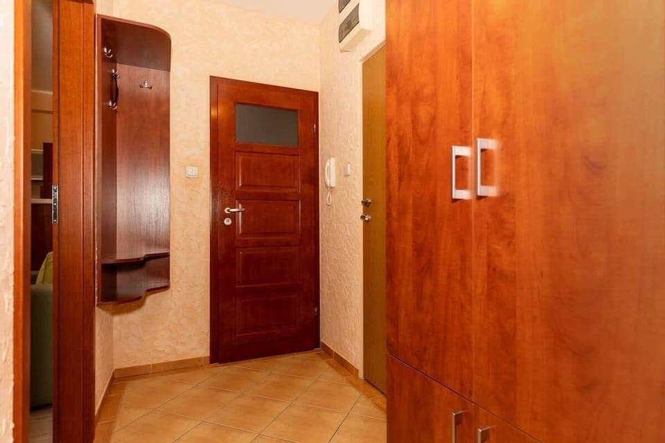 A spacious hallway with light-colored walls and tiled flooring, leading to the apartment’s other rooms.