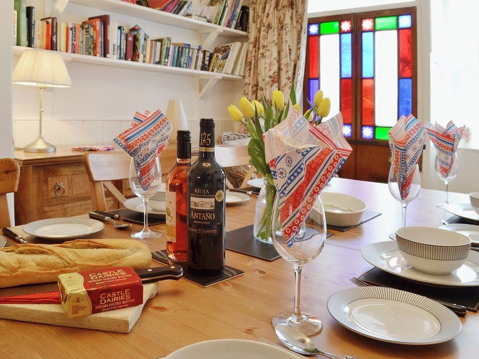 The quirky dining area has original stained glass door panels that cast a beautiful splash of colour over the walls | The Old Post Office, Myddfai, near Llandovery