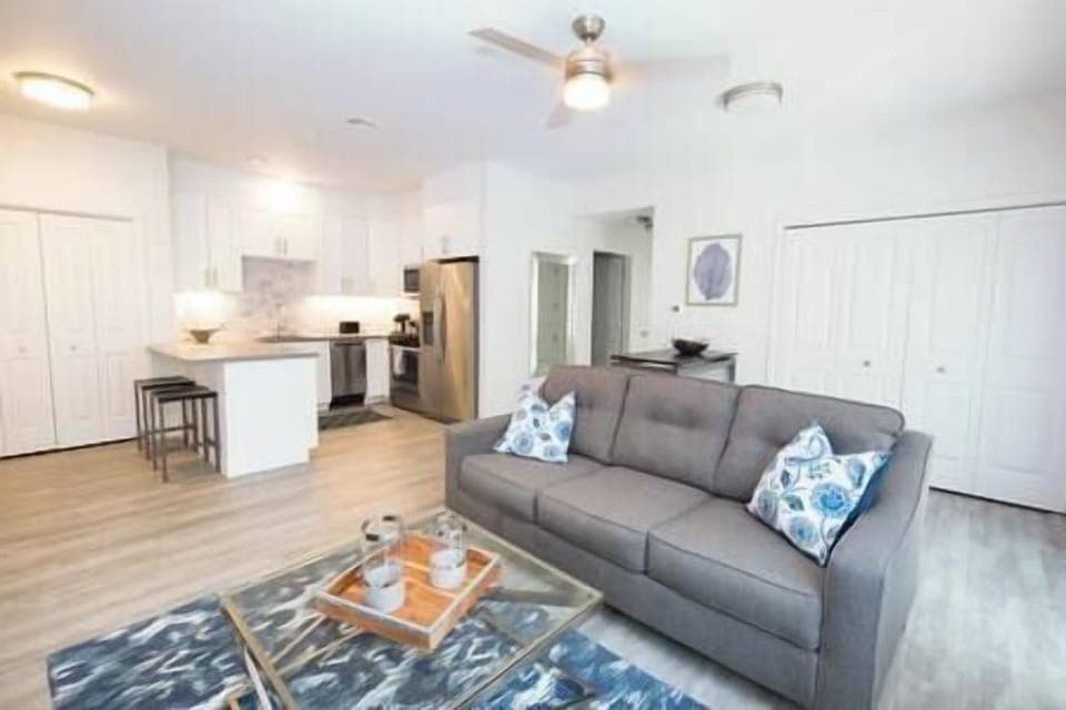 Cozy living area with couch, smart TV, full kitchen, bar seating, dining table, and patio access (2)