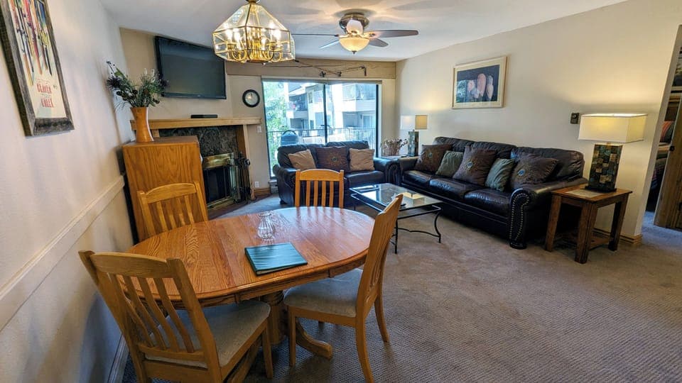 BC West J-3 Living room w/ dining table, wood fireplace, and balcony w/ gas BBQ