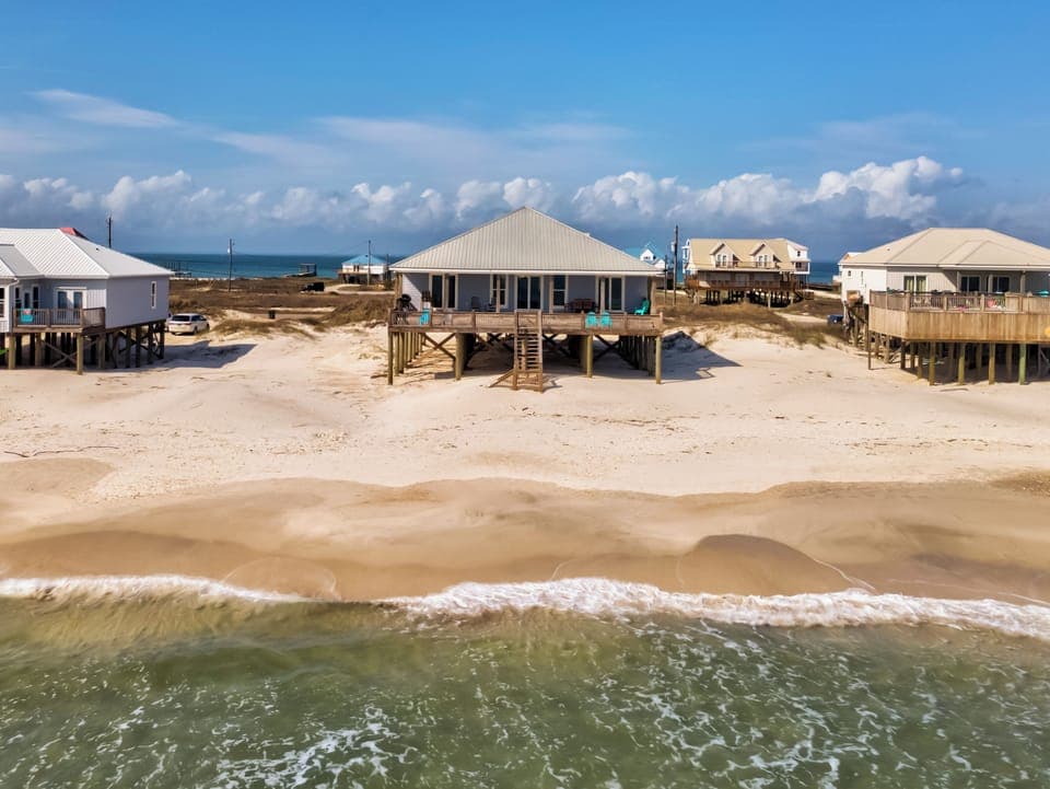 Beachfront vacation homes elevated on stilts along pristine sandy shores with direct ocean access.