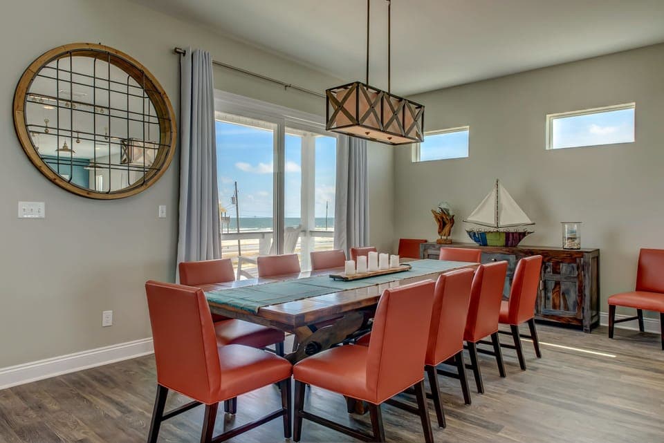 Gather around this spacious dining table where ocean views through floor-to-ceiling windows create the perfect backdrop for memorable meals together.