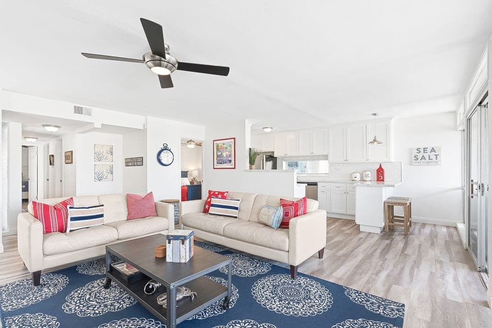 The living area includes leather sofa set, cable TV, and access door to the outdoor deck.
                