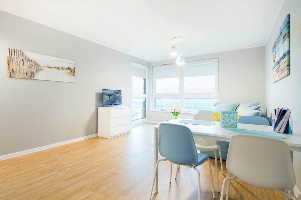 A view of the open-plan living and dining area, with the sofa and a small dining table. The space is styled with simplicity and comfort in mind.