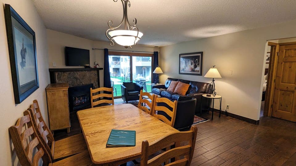 Living room with sofa bed, gas fireplace, dining table, and patio with gas BBQ