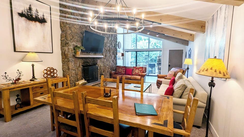 Living room with wood fireplace, dining table, and balcony w/ propane BBQ grill