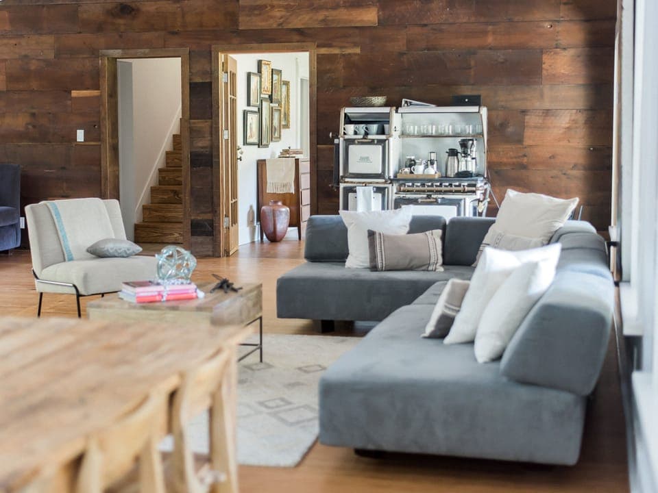 The Great Room features a fireplace, comfy sofas, and a large wooden farm table.