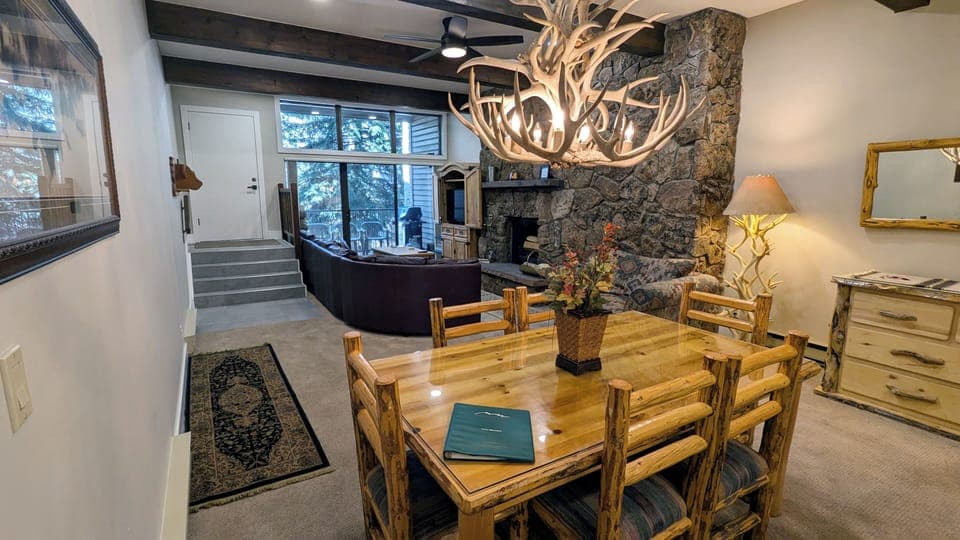 Living room with wood fireplace, dining table, and balcony with propane BBQ