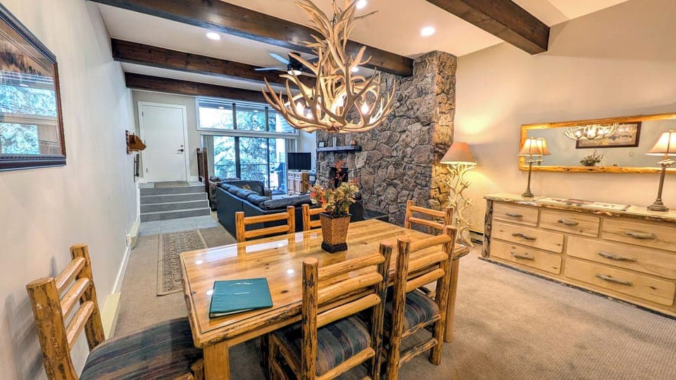 Living room w/ wood fireplace, dining table, and balcony with propane BBQ grill