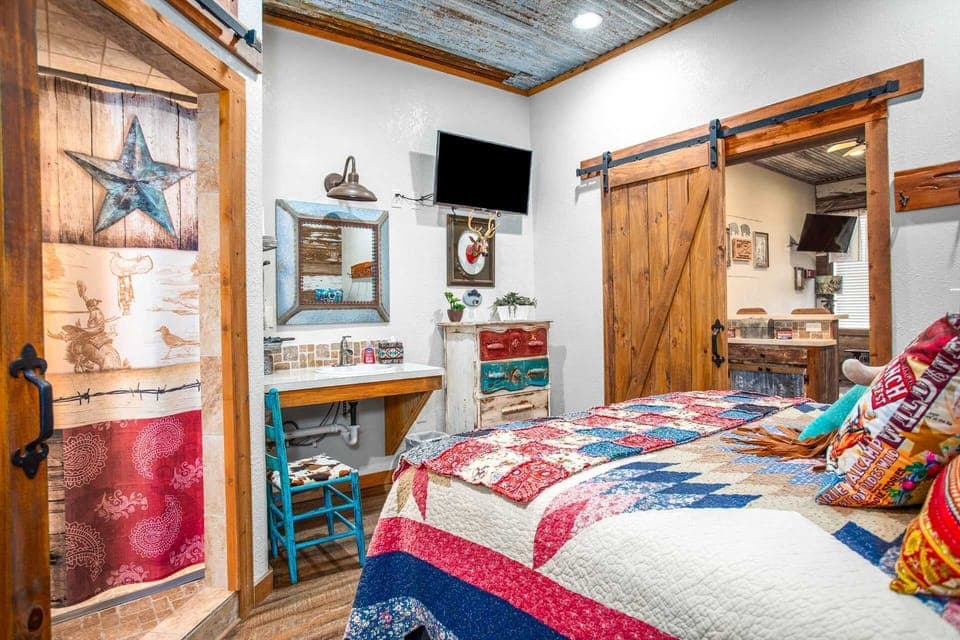 A plush queen-sized bed graces the bedroom at Lonesome Dove, with a fantastically western-style barnboard door for privacy.