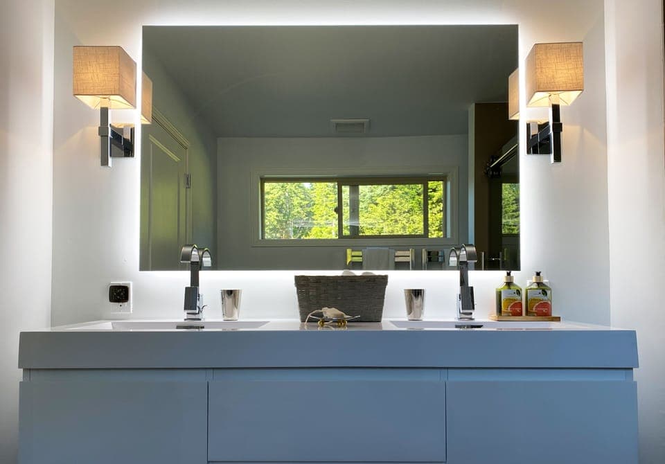 Stylish hanging vanity with backlit mirror over the double sink.