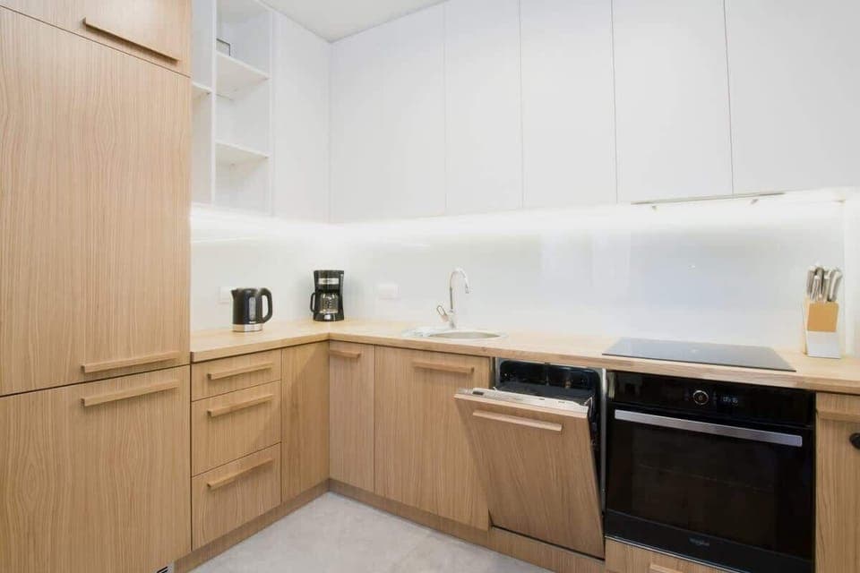 A contemporary kitchen with wooden cabinets and white countertops, equipped with modern appliances and designed with functionality and style in mind.