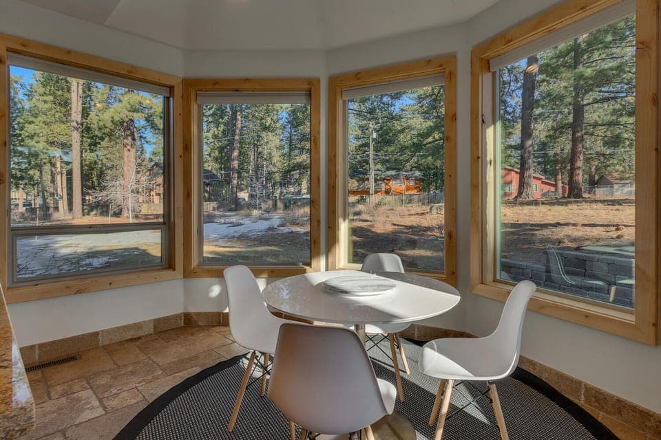 - Breakfast nook surrounded by windows with forest views  
- Modern round table with seating for four in bright corner  
- Peaceful space to enjoy morning coffee or casual meals