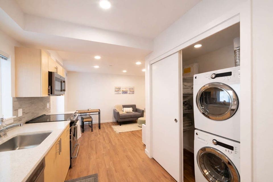 Modern kitchenette with stainless appliances, ample storage, and in-unit washer and dryer for a convenient, comfortable stay.
