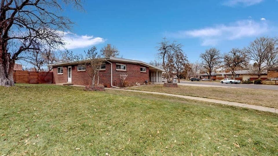 Spacious side yard with a well-maintained lawn, mature trees, and a charming brick home in a peaceful neighborhood.