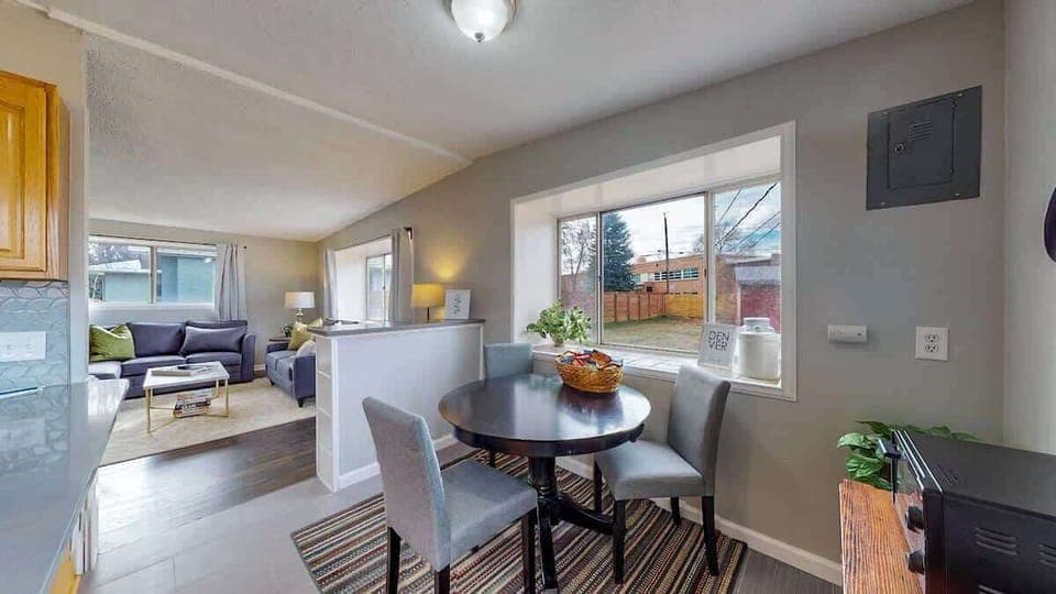 Bright dining area with a round table, cozy seating, and a large window overlooking the backyard.