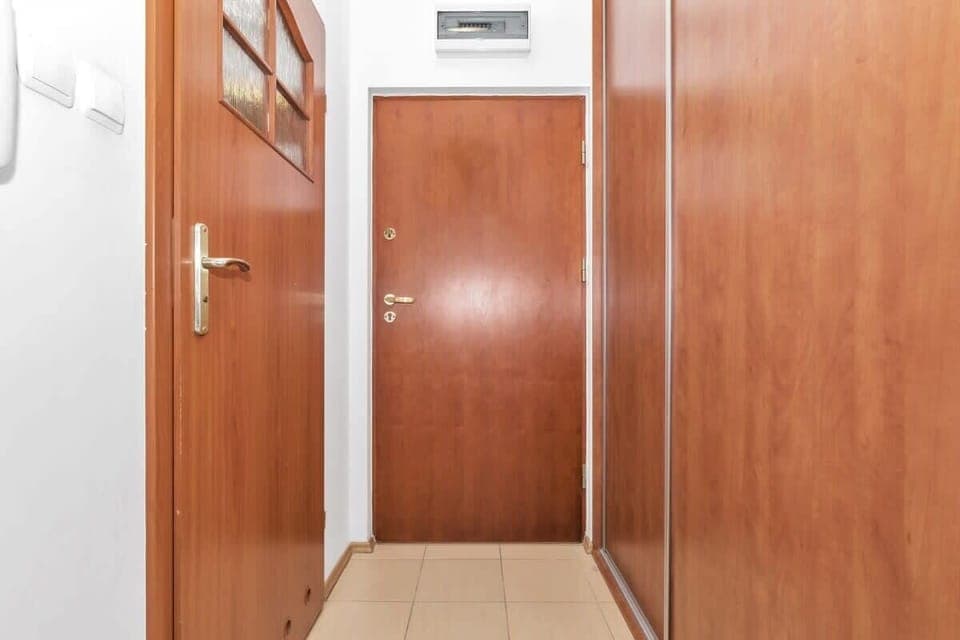 A hallway with wooden doors and built-in closets provides a practical entry space. The sleek design and neutral tones make it a functional yet attractive area.