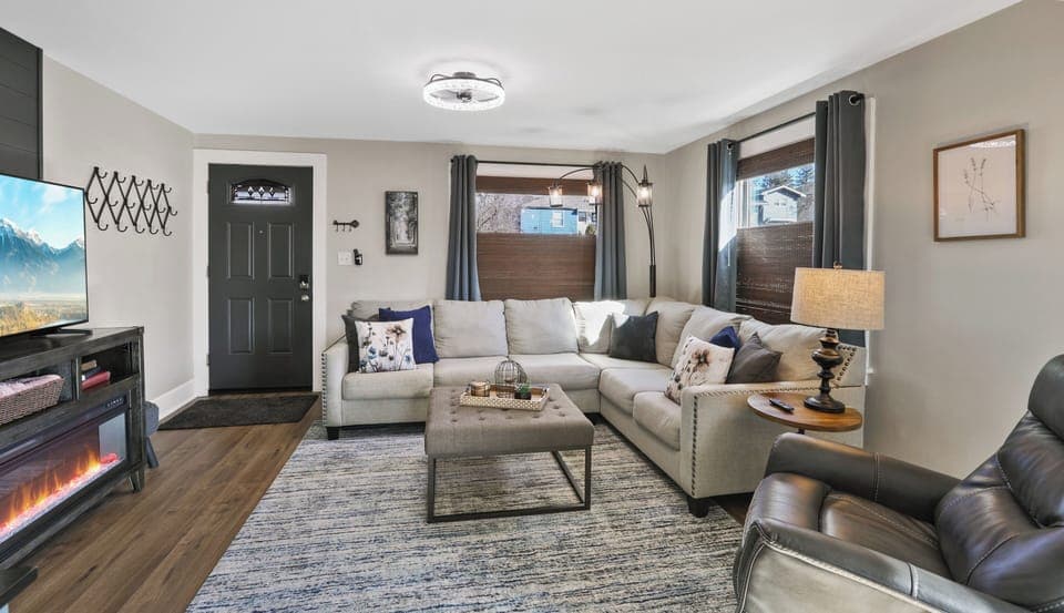 Comfy living room with large screen TV and blackout blinds.