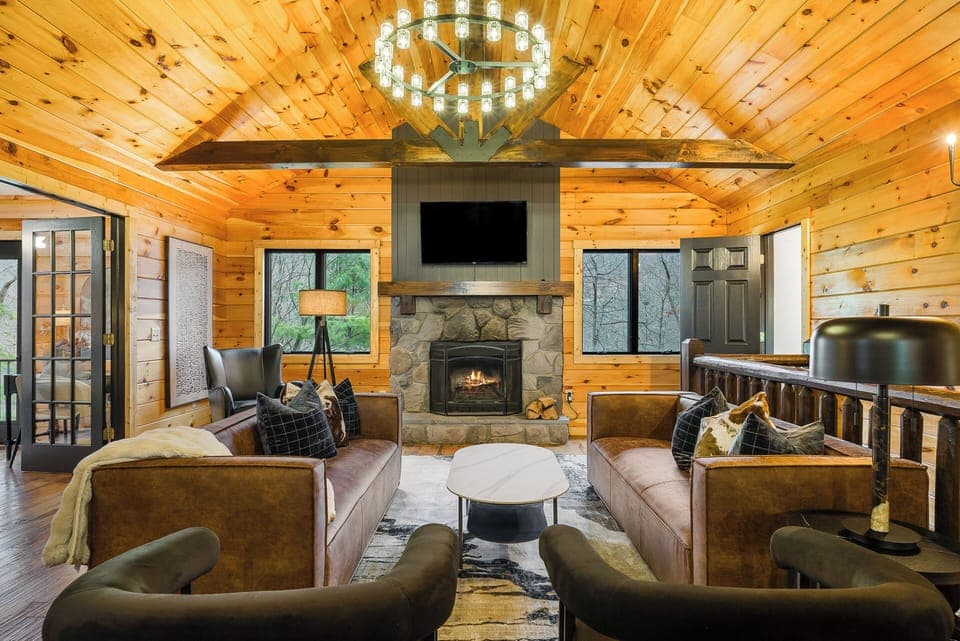 Relax by the crackling wood-burning fireplace in a comfortable living area featuring hardwood floors, leather seating, wood accents, and a smart TV.