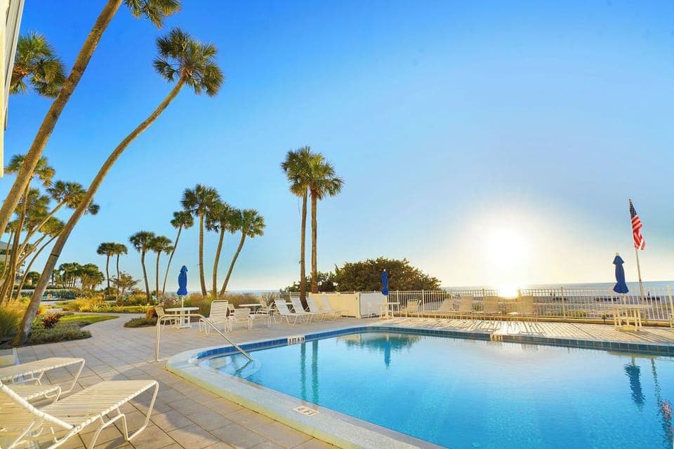 Resort-style oceanfront pool surrounded by palm trees, offering the perfect spot to relax during your beach vacation