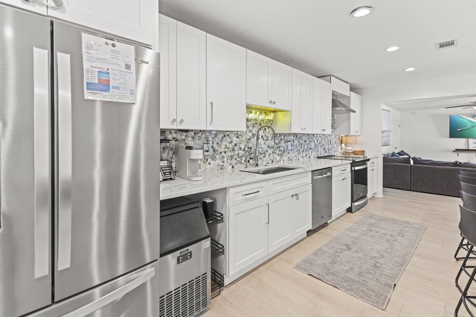Your sleek modern kitchen features stainless steel appliances and pristine white cabinetry, perfect for preparing memorable meals during your stay.