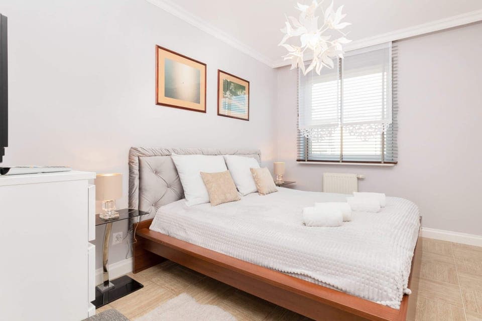 The main bedroom with a double bed, stylish bedding, and artwork on the walls. A bright and airy feel is created by the natural light from the windows.