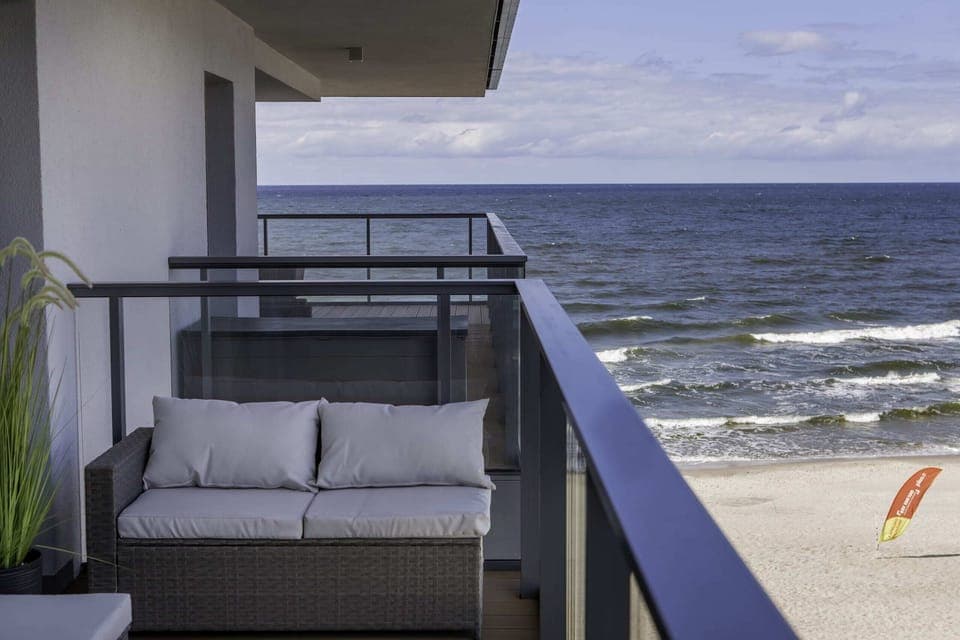 A cozy balcony with modern seating and a stunning view of the sea in the background.