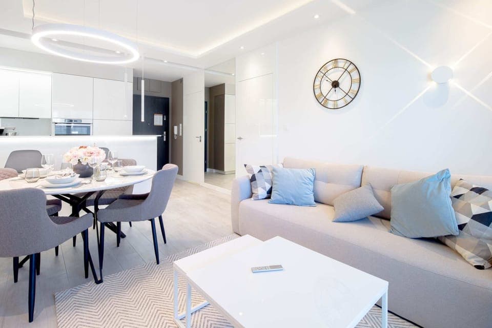 A dining table and chairs set in a contemporary living space with neutral decor and modern lighting.