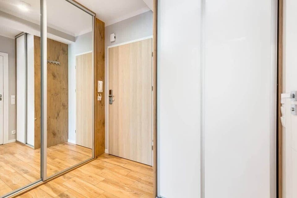  hallway in an apartment building, showcasing the mirror and clean, minimalistic design.