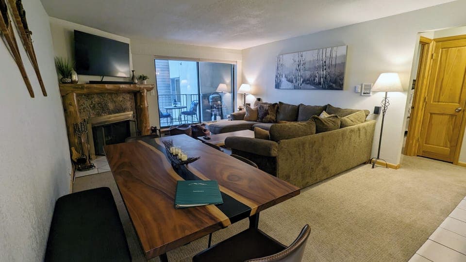 Living room with sofa bed, wood fireplace, dining table, and balcony w/ gas BBQ