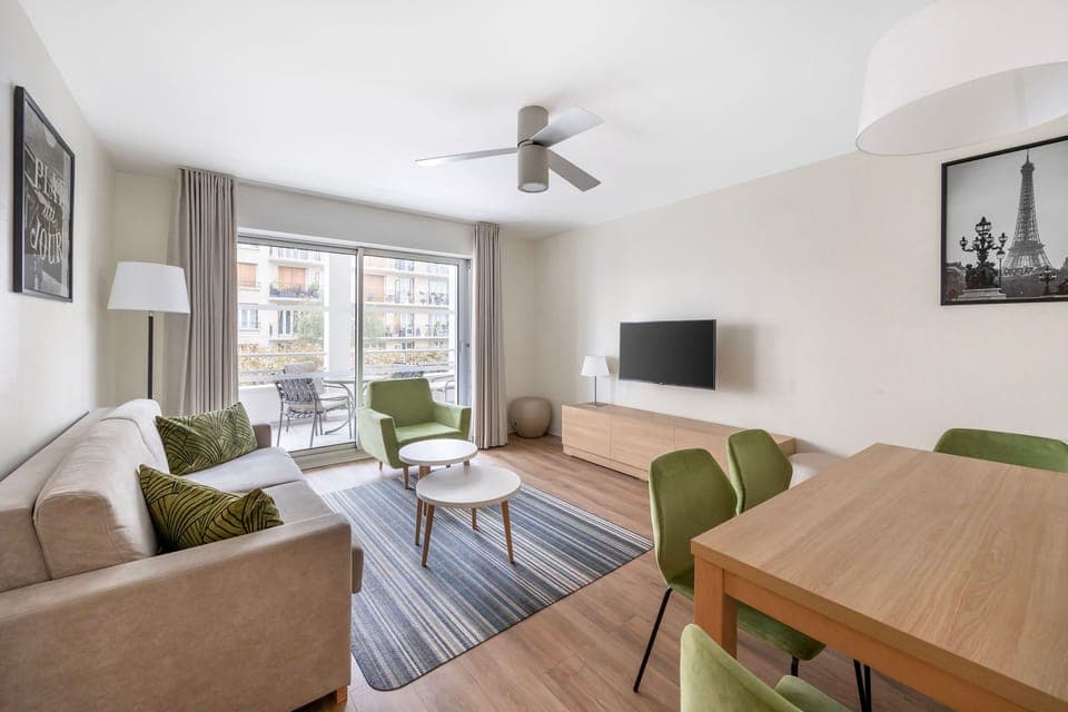 Bright and spacious living room with comfortable seating, a smart TV, and access to the private balcony for relaxation after a busy day.