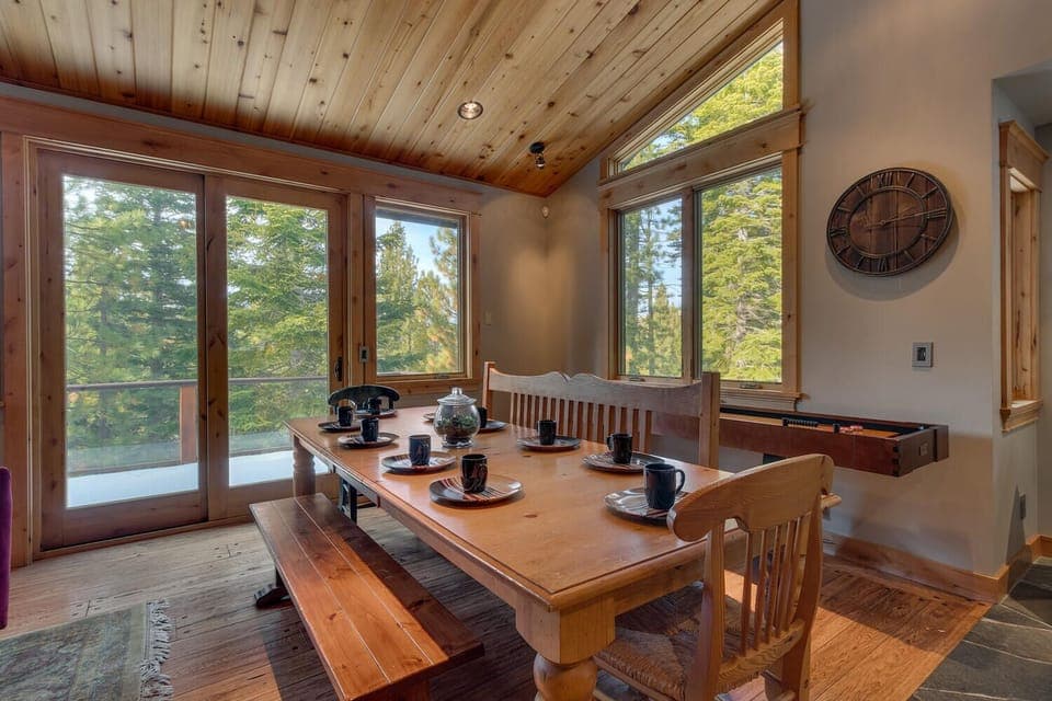 - Dining area with large wood table and bench seating  
- Surrounded by windows offering forest views  
- Tahoe vacation home perfect for group meals