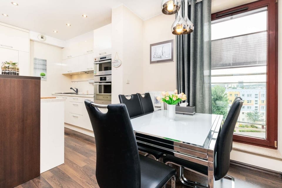 Dining area by the window with a modern table and a view of the surroundings.
