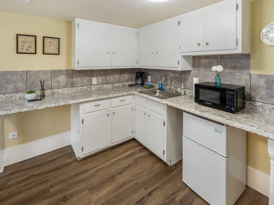 Kitchenette with microwave, coffee maker, mini-fridge, dishes, towel, sponge, soap and paper towels.