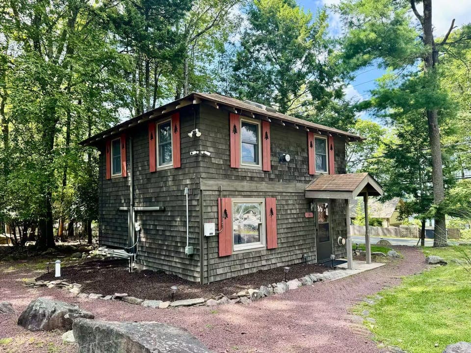 Charming two-story lake view cabin with colorful shutters and boulders