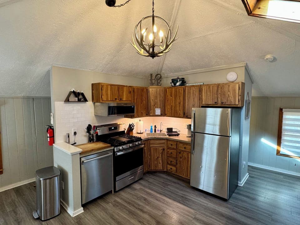 Cozy kitchen with gas range, dishwasher, and antler chandelier